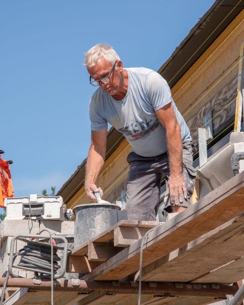 the bricklayer makes the facade of the house from gray bricks with cement and plaster at the construction site. High quality photo